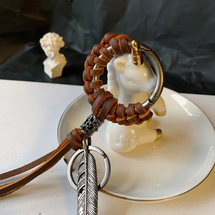 Portachiavi in ​​pelle intrecciata con piuma in metallo vintage e nappa