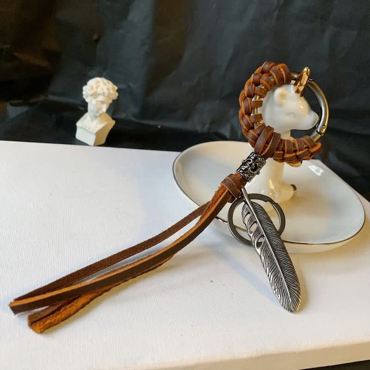 Portachiavi in ​​pelle intrecciata con piuma in metallo vintage e nappa
