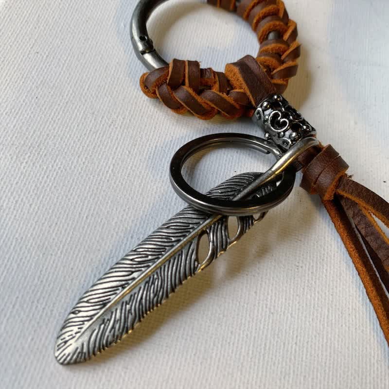 Portachiavi in ​​pelle intrecciata con piuma in metallo vintage e nappa