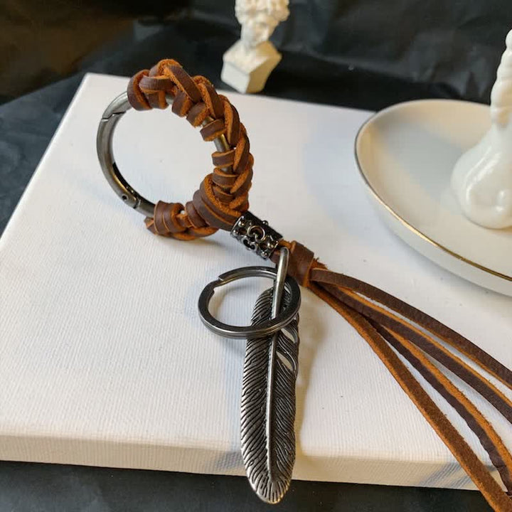 Portachiavi in ​​pelle intrecciata con piuma in metallo vintage e nappa