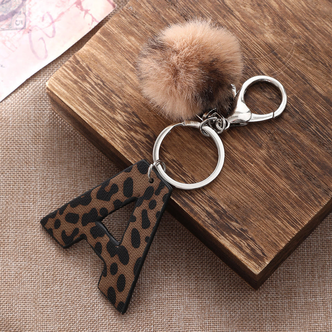 Portachiavi in pelle con lettera stampata leopardata in stile western e palla di peluche - image 0